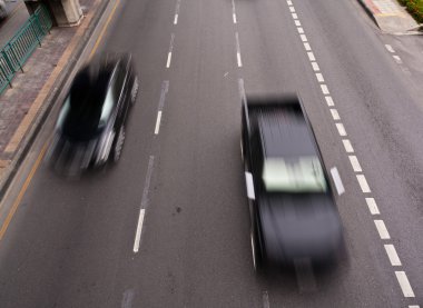 Two black cars running on the road clipart