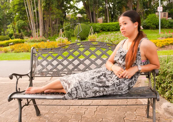 Рассеянные азиатки лежат на скамейке в парке — стоковое фото
