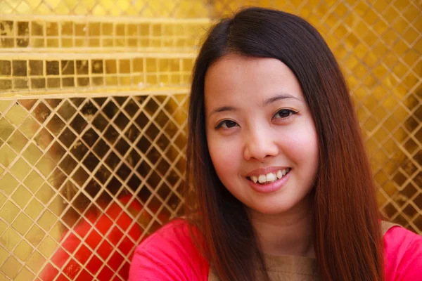 バック グラウンドで黄金のタイルに笑みを浮かべてタイの女性 — ストック写真