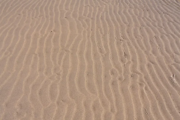 Textura de fundo de areia através da ondulação água do mar tiltrd para fora — Fotografia de Stock