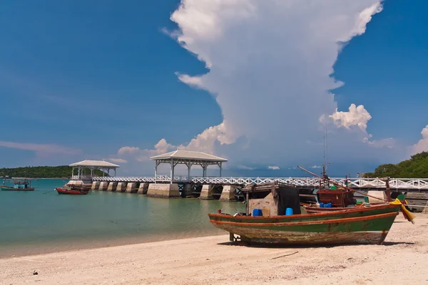 Träbåt på stranden med träbro från sidan — Stockfoto