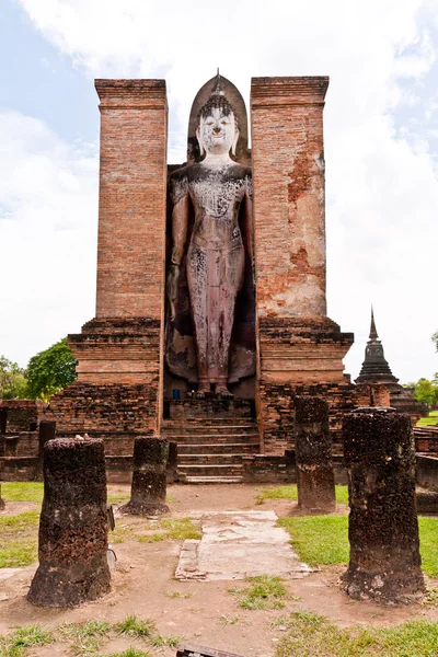 Standing Buddha statue behind pillars vertical — Stock Photo, Image
