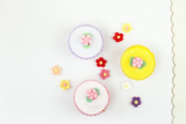 Festve cupcakes with sugar flowers on white linen table clipart