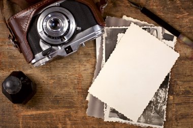 Vintage ink and pen, old photos and camera on old wooden table clipart