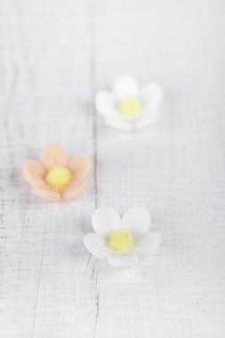 Three sugar blossom flowers on white old table clipart