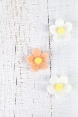 Three sugar blossom flowers on white old table clipart