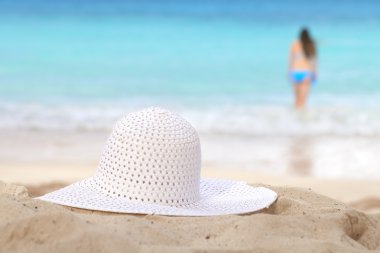 White sun hat on beach girl going to swim and sea on background clipart