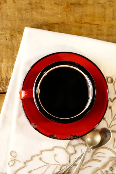 Black coffee, red enamel mug, two old silver spoons on embroider — Stock Photo, Image