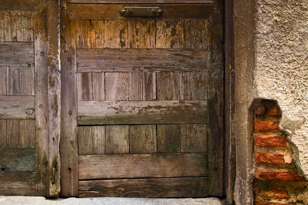 Очень старая деревянная дверь и обветшалая кирпичная стена, фрагмент — стоковое фото
