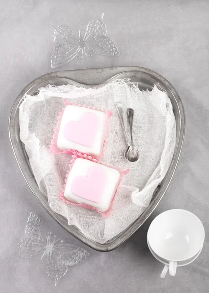 Růžové košíčky v srdci tvaru cínu s lžíce a pohár — Stock fotografie