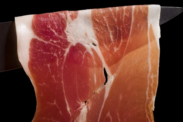 Segment van droge gerookte ham op een mes — Stockfoto