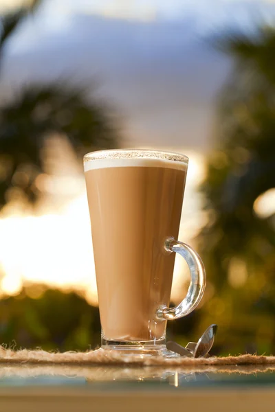 Caffè latte in palma e sfondo tramonto — Foto Stock