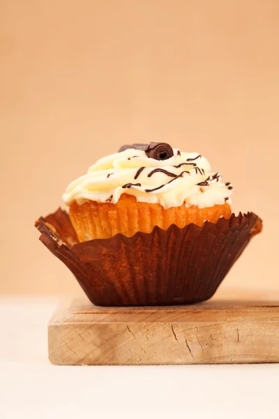 Cupcake avec glaçage au citron partiellement déballé sur une planche de bois — Photo