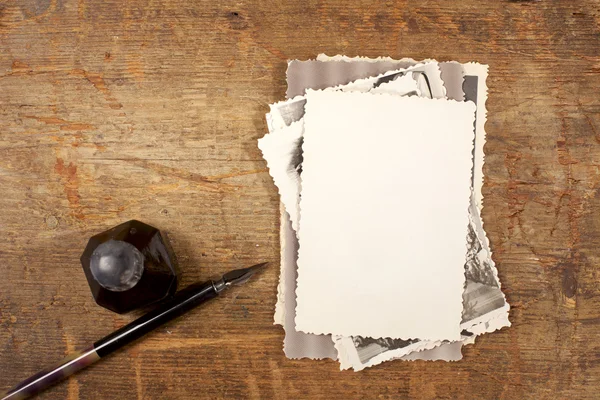 Ročník inkoustové pero, kalamářů a staré fotografie na dřevěný stůl — Stock fotografie