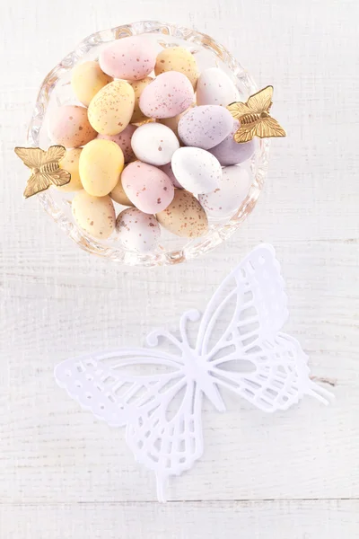 Chocolate speckled eggs in bowl with paper batterfly on white ta — Stock Photo, Image