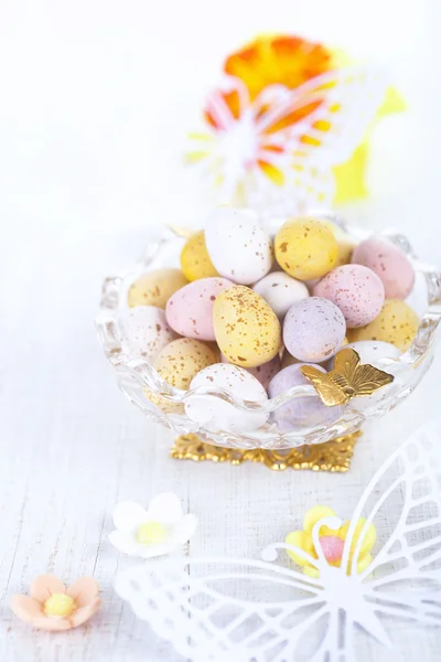 Chocolate speckled eggs in bowl with paper batterfly on white ta — Stock Photo, Image