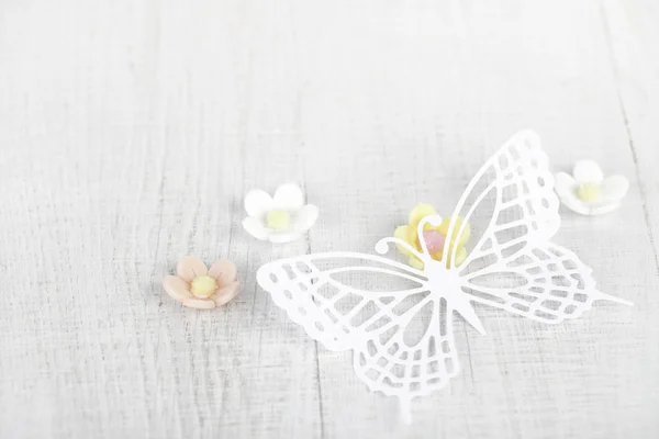 Paper butterfly and three sugar blossom flowers on white old tab — Stock Photo, Image