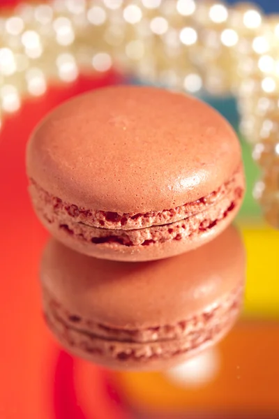 Macaron red with its own reflection colorful backdrop and pearl — Stock Photo, Image