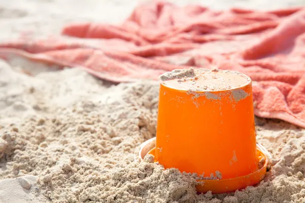 Beach bucket tiy and towel on beach sand, shallow dof — Stock Photo, Image