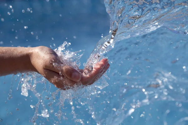 Meninas mão pegando água, em águas azuis fundo — Fotografia de Stock