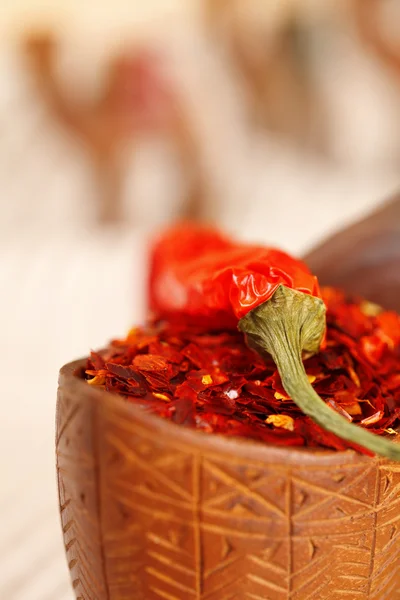 Red chillies paper in curved wooden bowl and camel caravan silh — Stock Photo, Image