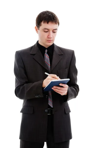 Ein junger Mann im Anzug, schreibt in ein Notizbuch. — Stockfoto