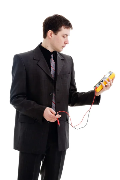 A young man in a suit, looks at the testimony of a multimeter. — Stock Photo, Image