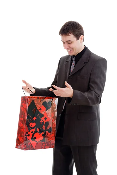 Joven, hombre feliz en un traje, mira en la bolsa . — Foto de Stock