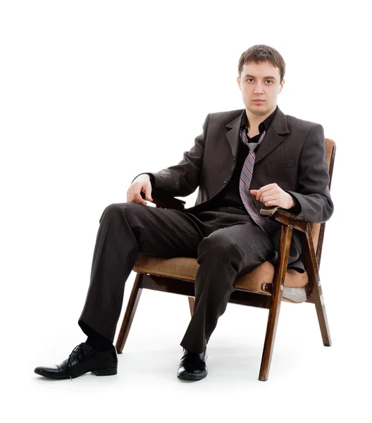 Egy fiatal férfi öltöny, nyakkendő, ül egy széken. — Stock Fotó