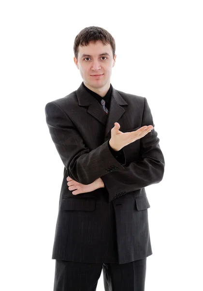 Μια νεαρή, χαμογελαστό άνθρωπο σε ένα κοστούμι δείχνει ένα χέρι. — Φωτογραφία Αρχείου
