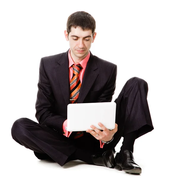 Młody człowiek siedzi na podłodze i zegarki na laptopie. — Zdjęcie stockowe