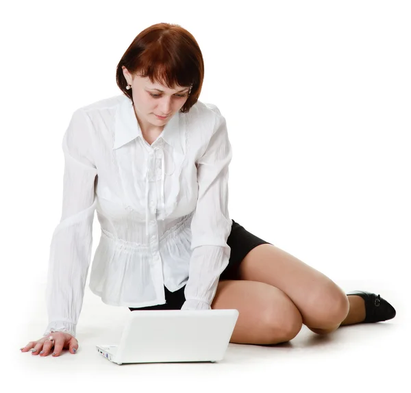 Jovem mulher sentada no chão e assiste em um laptop . — Fotografia de Stock