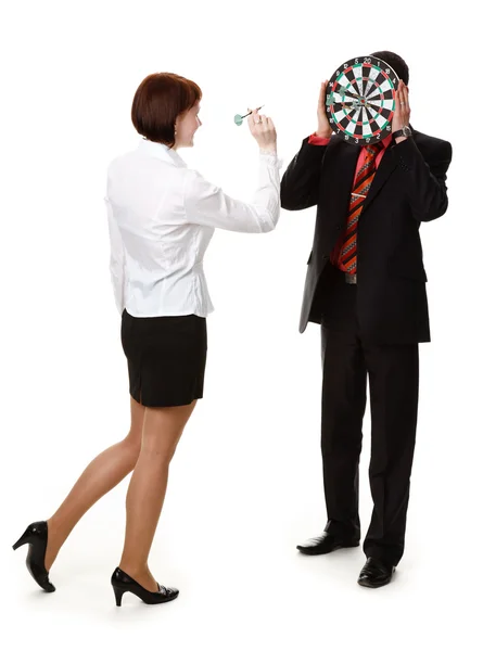 Young woman throwing darts at a target held by the man. — Stock Photo, Image