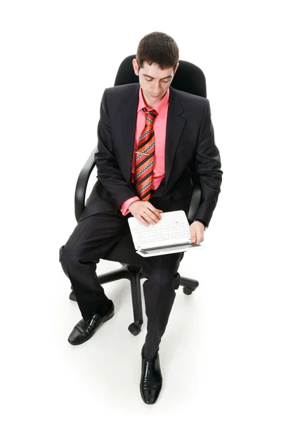一个年轻男子坐在椅子上和工作上一个笔记本. — 图库照片
