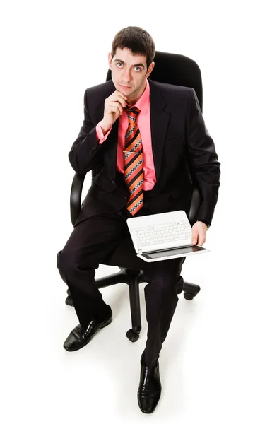 Um jovem de terno, sentado em uma cadeira com um laptop . — Fotografia de Stock