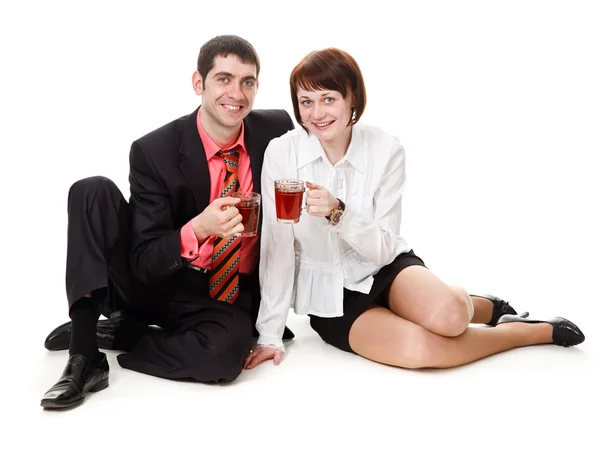 Молодые, улыбающиеся, сидящие на полу женщина и мужчина, пьющие чай — стоковое фото