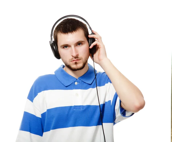 En ung kille med ett skägg, lyssna på musik i hörlurar. — Stockfoto