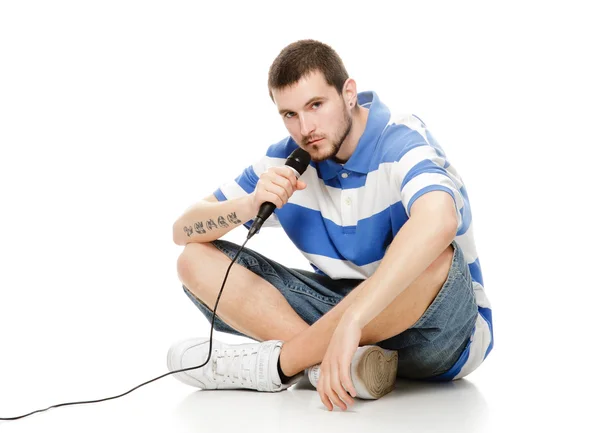 Young guy with a microphone, sitting on the floor. — Stock Photo, Image