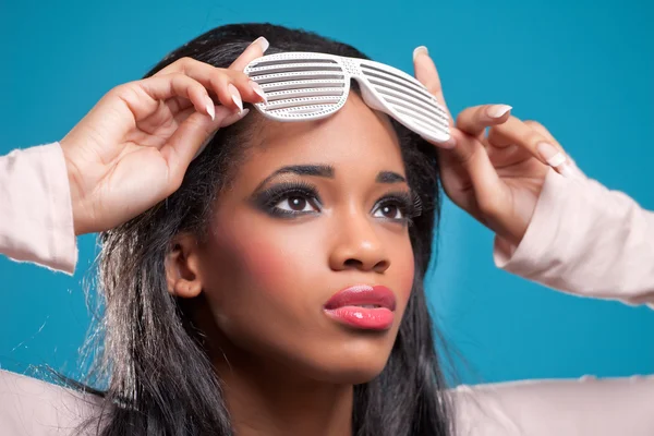 Schöne junge Frau mit schicker Sonnenbrille, isoliert auf blauem Grund — Stockfoto