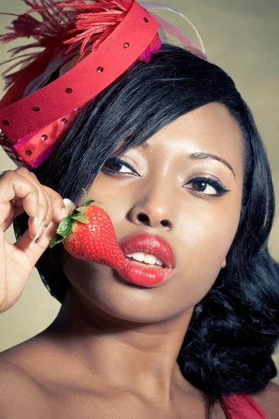 Beautiful young black woman eating a strawberry — Stock Photo, Image