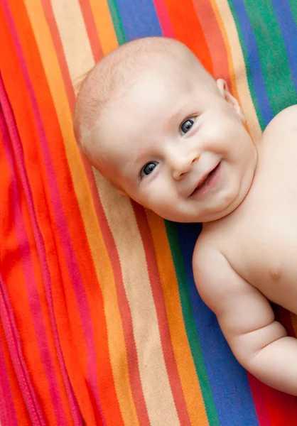 줄무늬 배경에 누워 웃는 아기 — 스톡 사진