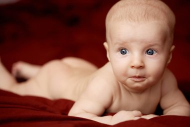 Bordo yatak örtüsü üzerinde çocuk