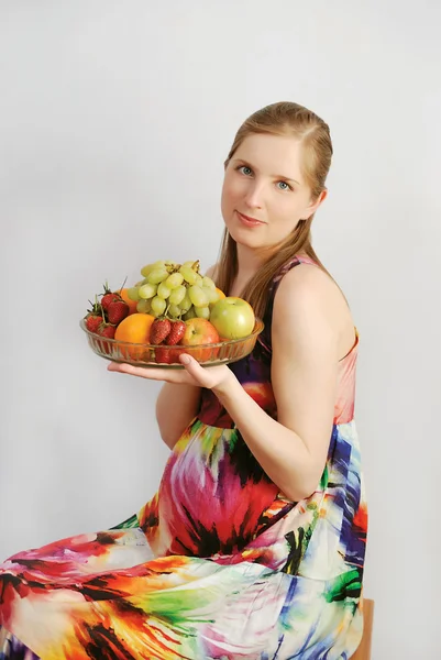 Stock image The pregnant young woman with a dish of fruit