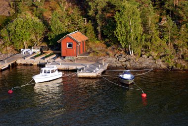 Mooring with a small house and boats in Sweden clipart