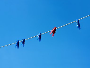 Clothes-line and pegs on blue sky background clipart