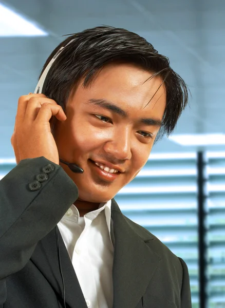 Männlicher Außendienstmitarbeiter in seinem Büro im Gespräch mit einem Headset — Stockfoto