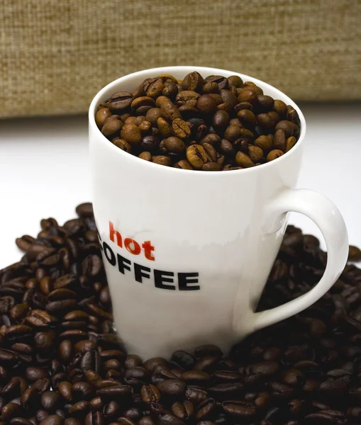 Una taza de café caliente con granos de café —  Fotos de Stock