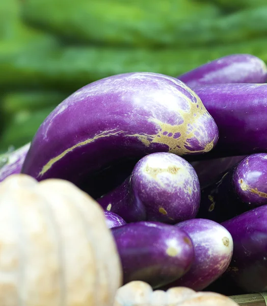 Organic eggplants and pumpkins in a market — Stock Photo, Image