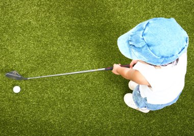 üzerinde yeşil koyarak Golf oynayan küçük çocuk