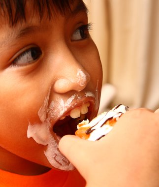 Child With A Messy Face Eating A Cream Cake clipart